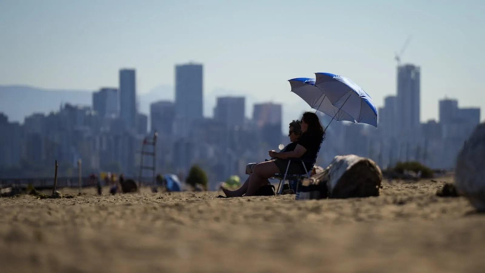 People sit under umbrellas at Locarno Beach in Vancouver on Wednesday, Aug. 16, 2023. THE CANADIAN PRESS/Darryl Dyck